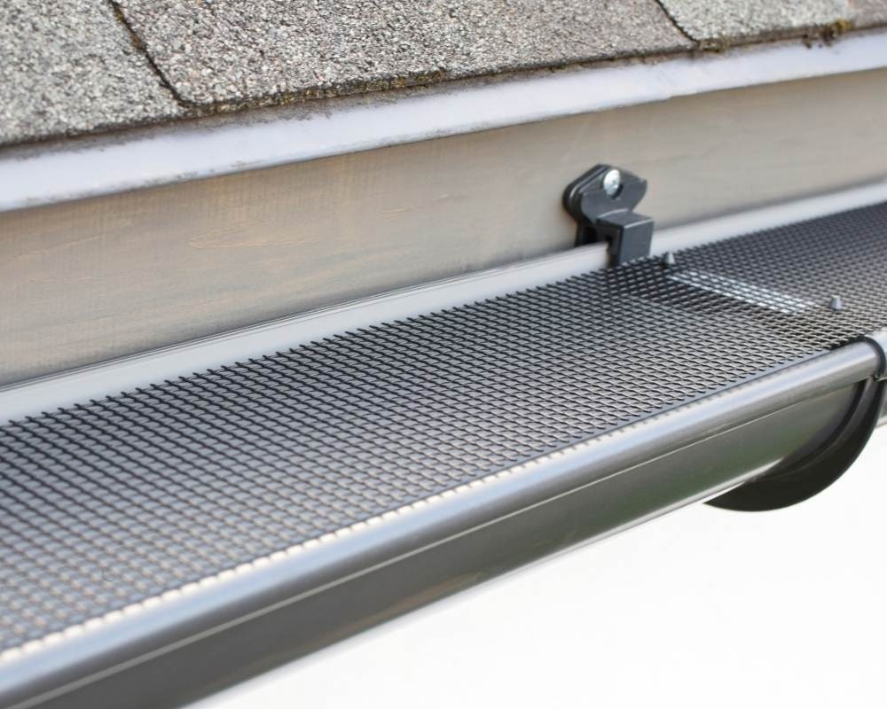 Technician clearing roof gutters to prevent rainwater backup